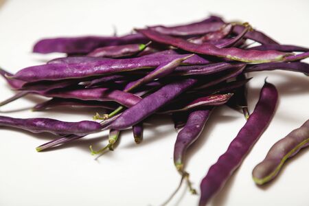 Beautiful pods of purple beans lie on a white background close-upの写真素材