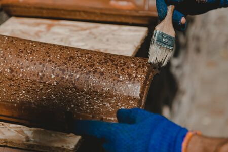Hands cover ceramic tiles with water-repellent mix using a close-up brush.の写真素材