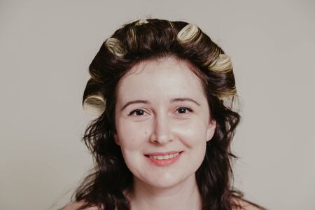 Female portrait without retouching with its natural imperfections. Long hair twisted on curlers