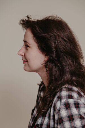 Profile portrait of an attractive girl with natural imperfections in a stylish plaid shirt on a gray backgroundの写真素材