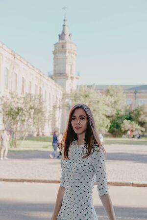Cute young student with long hair in a denim jacket walks on campus in the autumn afternoonの写真素材