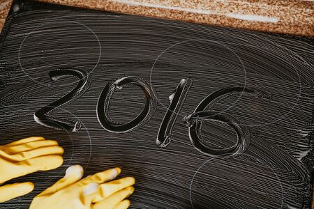 New Year in the kitchen. 2016 is written on a surface covered with soapy foam. Nearby lies a yellow...
