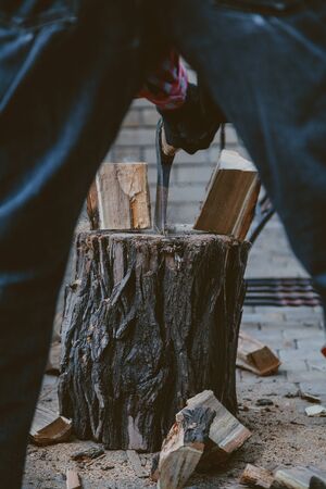 man chops with an ax log on the stump. Rear view between the legsの写真素材