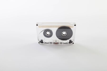 Audio cassette for tape recorder with a transparent plastic case on a white background close-up