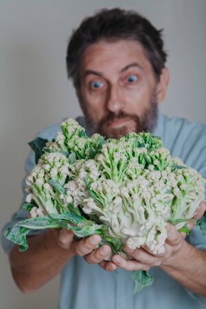 man with a beard is holding a cauliflower head in close upの写真素材