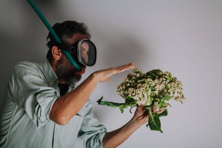 Cauliflower or coral. Comic story. A man with a beard and a swimming mask holds a cauliflower head in his hand like sea coralの写真素材
