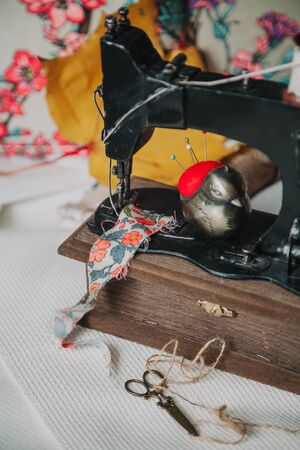 Vintage sewing machine. On the bed lies a flap of colorful fabric and a stylish chicken-shaped...