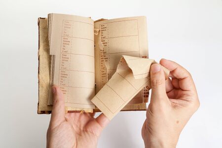 Man right hand pulls a page out of the middle of an notebook with an alphabetical index