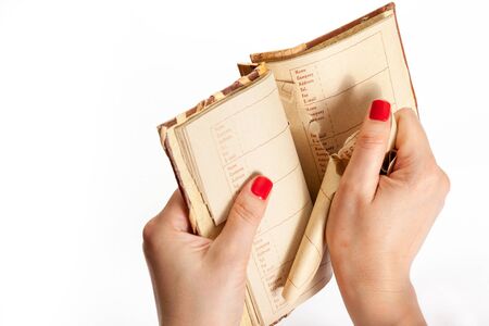 emotional act. Female hand with red manicure tears a page out of a notebook with an alphabetical...