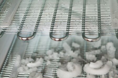freezer is defrosting. Modern fridge with open door close-up. Inside empty shelves and pieces of ice...
