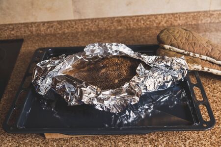 Fish baked in foil lies on a black metal pan on a granite countertop
の写真素材
