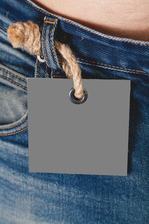 gray paper label hangs on a loafer of jeans on a thick rope with a large knot
の写真素材