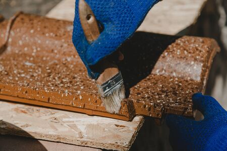 Hands cover ceramic tiles with water-repellent mix using a close-up brush.の写真素材