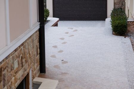 Winter has come. Trail track in the fresh white snow in the yard. Left wall of the houseの写真素材