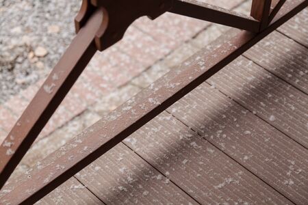 Snowflakes of snow lie on the floor and wooden structure of the fence of the veranda