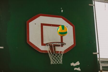 training basketball backboard weighs on a wall. A striped ball hovered over a ring with a net