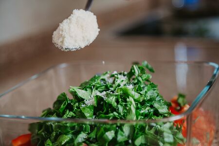 Appetizing salad of tomatoes and arugula covered with grated white cheese from a tablespoon