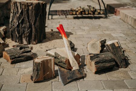 sawn dry acacia wood lies on a stone tile in the yard. A sharp ax rests on a log. There is a stump behindの写真素材