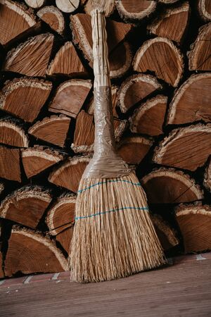 Chopped mulberry wood is densely stacked in several layers. Before them stands a broom.