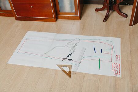 Sewing pattern lies on the floor. A silhouette of a garment is drawn on a paper sheet. On top is a...