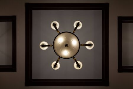 Round chandelier on a white background. View from below. Around six small shades. Near the square...