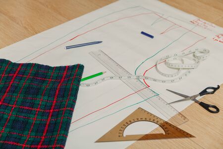 Still life on the sewing pattern. On the paper sheet drawn silhouette of a garment. On top is a...