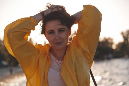 Portrait of a pretty plus size girl with long red hair and a bright yellow jacket in backlight...