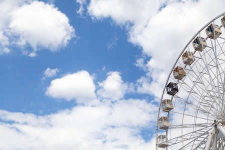 Viewing attraction. Cabins on the Ferris wheel against the blue sky with white cloudsの写真素材