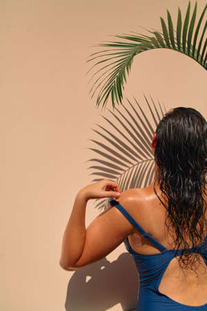 Portrait of a girl under a palm tree. Above a beautiful girl, a graceful bend of the green branch of...