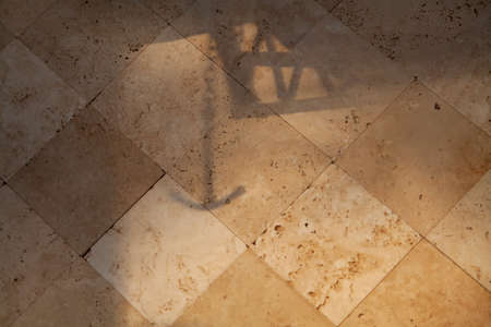 Anchor and chain shadow falls on a vertical wall with gray tiles