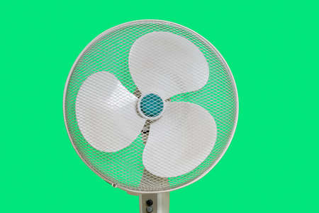 household fan with three blades isolated on green chroma key background. A round mesh casing is installed on topの写真素材