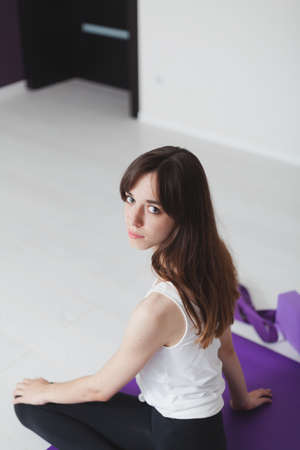 Cute graceful girl with long hair in tights engaged in yoga on a lilac rug