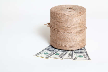 New roll flax cord standing on some banknotes on a white background