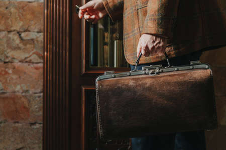 gentleman in a stylish checkered jacket holds a vintage and a bag
