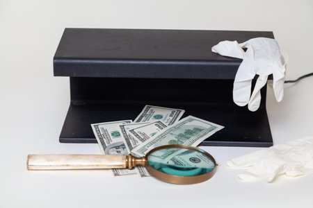 Verification of dollar bills using a close-up UV detector. Nearby lies a magnifying glass on a bone...