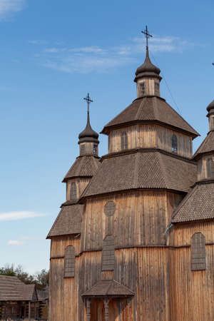 Wooden Christian temple with two domes against a blue sky. There are crosses on the domes