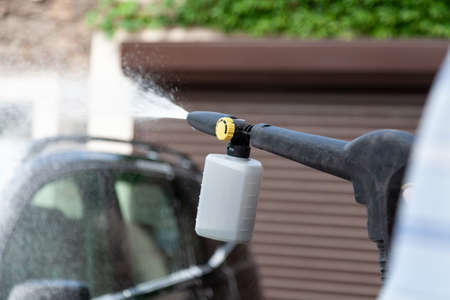 Washing a black car with special equipment with a high pressure water jetの写真素材