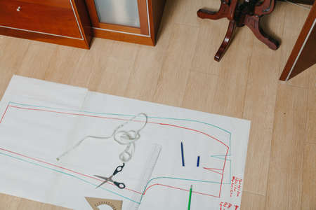 Sewing pattern lies on the floor. A silhouette of a garment is drawn on a paper sheet. On top is a...