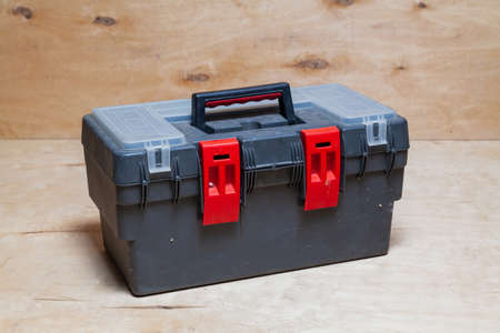 modern plastic closed toolbox stands against a light plywood background