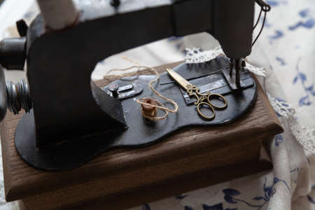 Sewing still life. Yellow vintage scissors lie on the bed of a manual sewing machine. There is a...