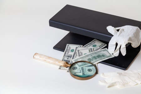 Verification of dollar bills using a close-up UV detector. Nearby lies a magnifying glass on a bone...
