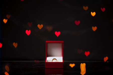 Valentine's Day gift. A silver ring stands in a red box on a dark background with multicolored...