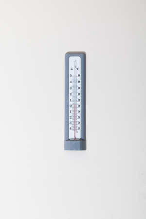 Thermometer with red liquid weighs vertically on the wall