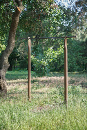Gymnastic equipment in the forest. An amateur crossbar on two metal posts is installed in front of a...