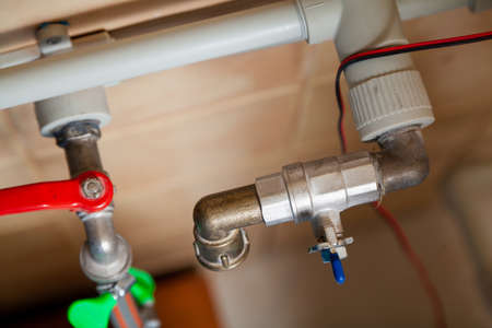 Two ball valves of different designs are perpendicularly mounted on gray plastic pipes. View from aboveの写真素材
