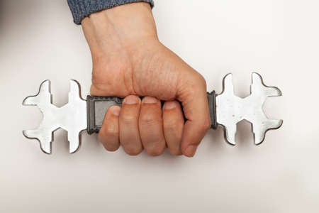 Hand holds firmly open-end wrench with metric and US standard on white background