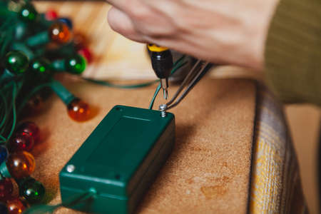 Preparing for the New Year. Repair of a Christmas tree electric garland. Hands open the control box...