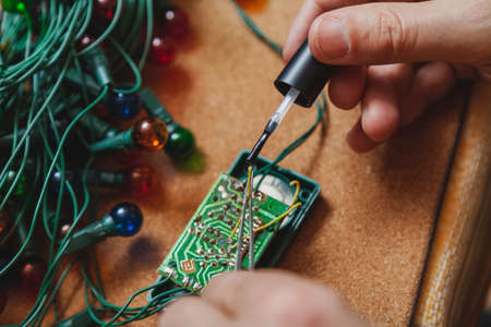 Preparing for the New Year. Repair of a fir-tree electric garland. In the hands of an electrician...