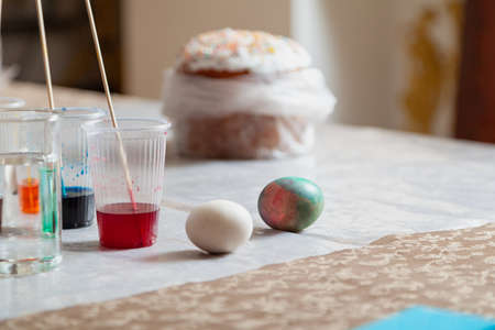 Homemade painted Easter eggs next to an Easter cake on a table for creativity and a container of...
