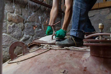 Hands of the installer in green gloves holds a metal hatch bracket with a screw lock on top of the large capacityの写真素材